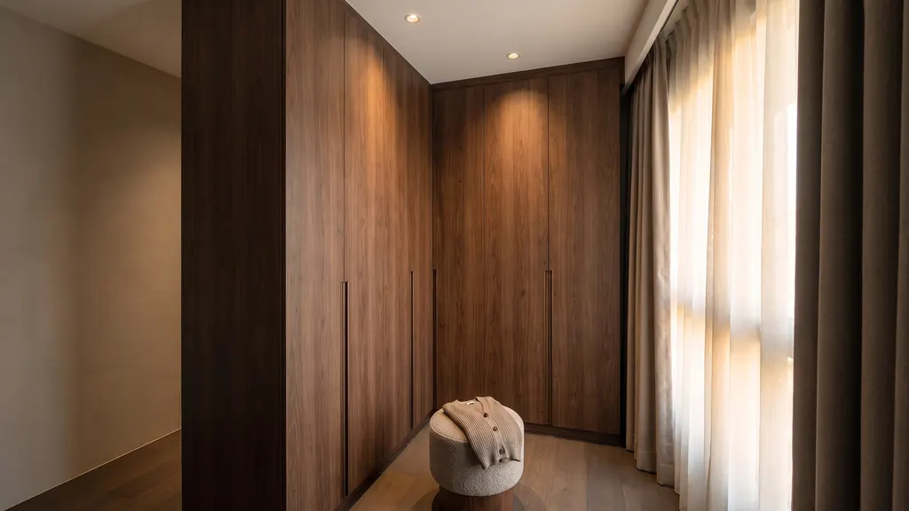 Photoreal render of the main bedroom wardrobe in the Ang Mo Kio 4-room HDB sample, Warm Modern Luxe: full-height dark walnut wardrobe, a round upholstered stool and curtains