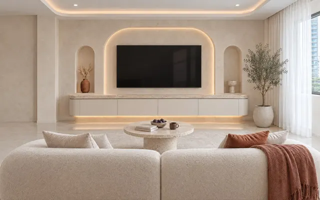 Living room in the Modern Cream theme: Cream tone on tone with terracotta and cocoa accents, curves everywhere: arches, flat handleless joinery with curved ends, round pedestal tables, honed pitted travertine and limewash walls in warm light